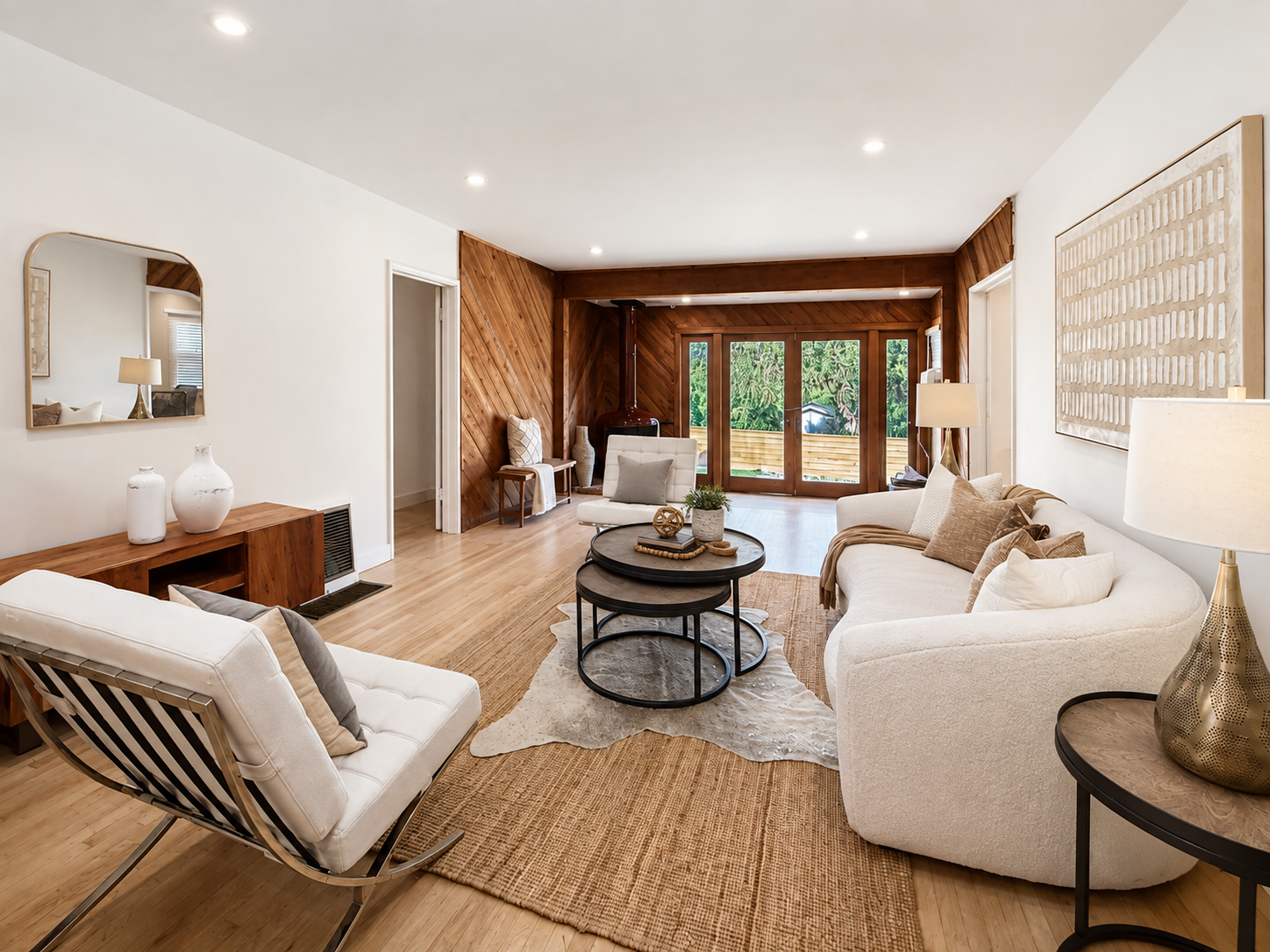 When Should a Los Angeles Listing Be Re-Staged and Relaunched? - KMW Interiors Abernathy living room staged with a curved sofa, accent chairs, and a clear view toward the wood-paneled rear room.